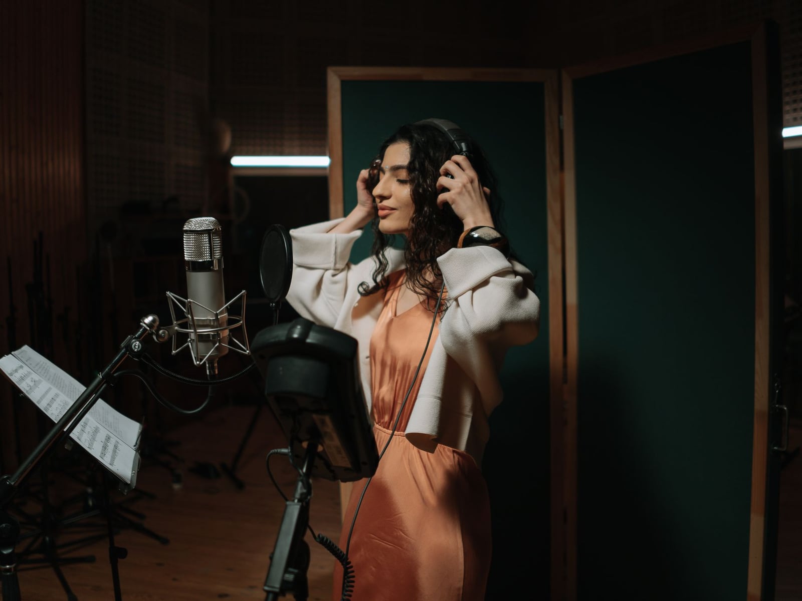 Cantante grabando voces en la cabina profesional de Sticketzyra con micrófono de condensador
